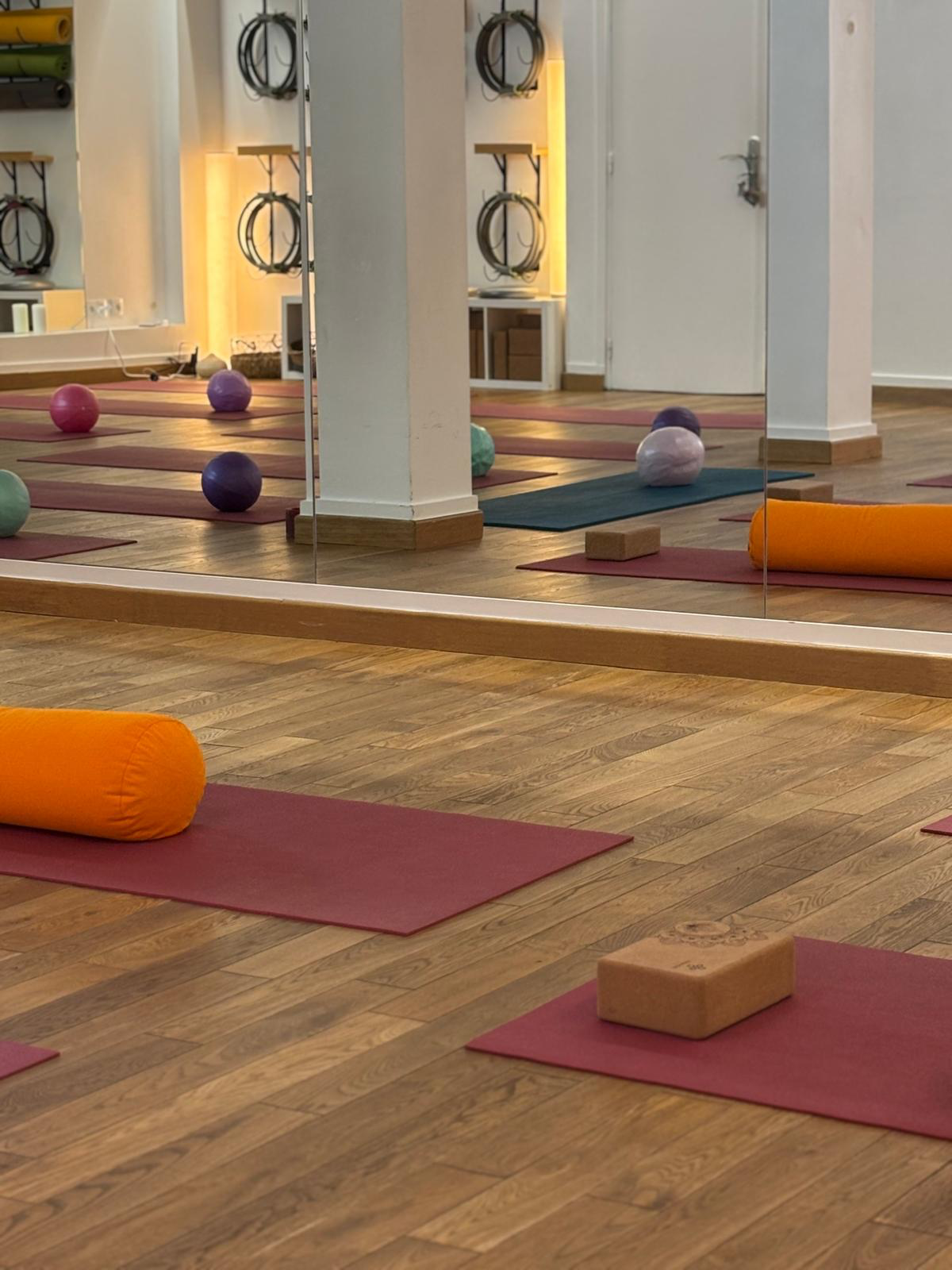 Reflet dans le mur miroir du studio : tapis, ballons de Pilates et bolsters