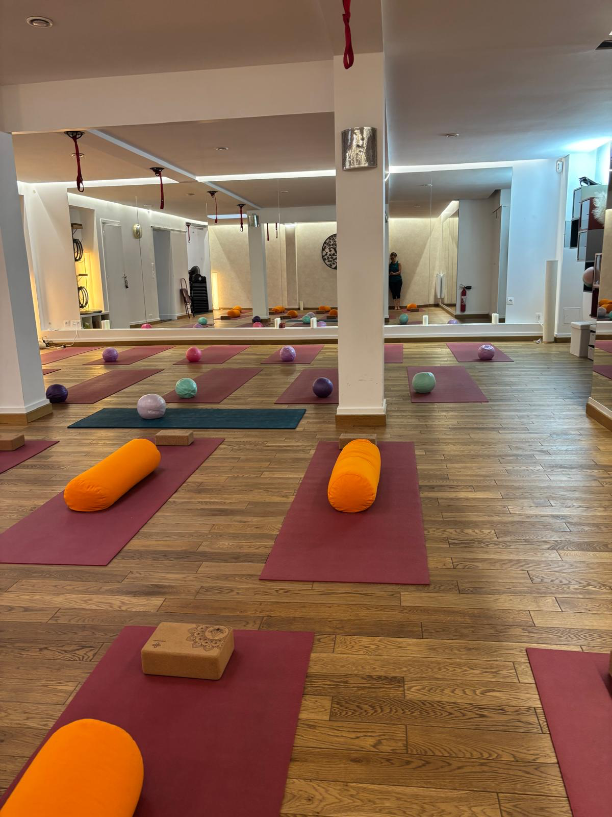 Vue de la salle du studio depuis le sol : tapis alignés, briques en liège et bolsters orange
