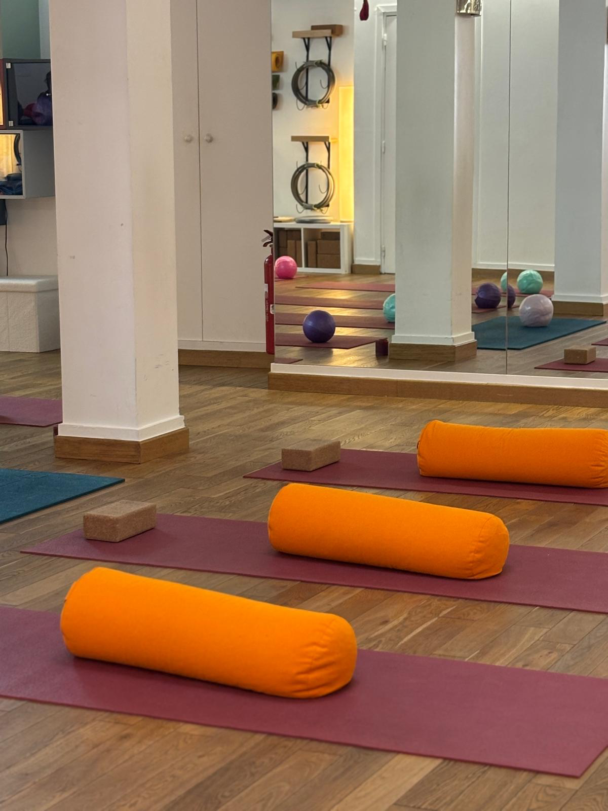 Tapis de yoga alignés avec bolsters orange et briques en liège au KSPORT STUDIO 7